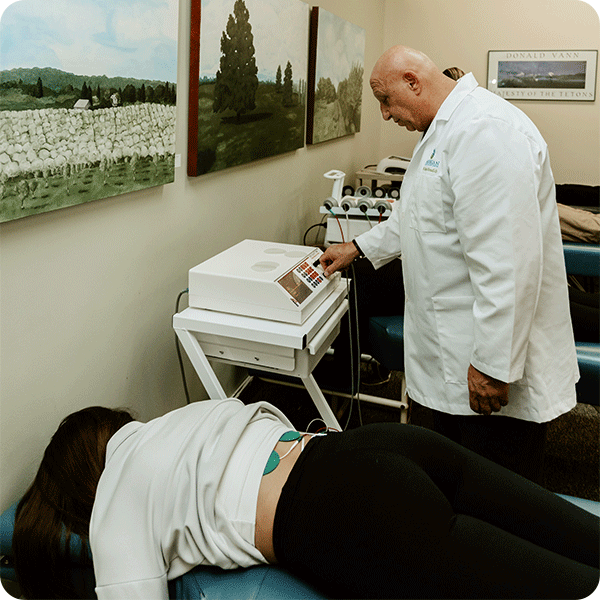 Doctor Tony using PEMF therapy on female patient's back