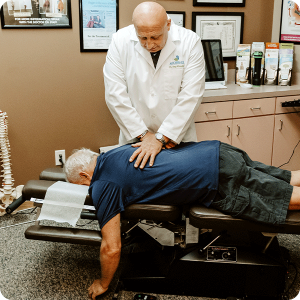Doctor Tony performing chiropractic adjustment on male patient's back