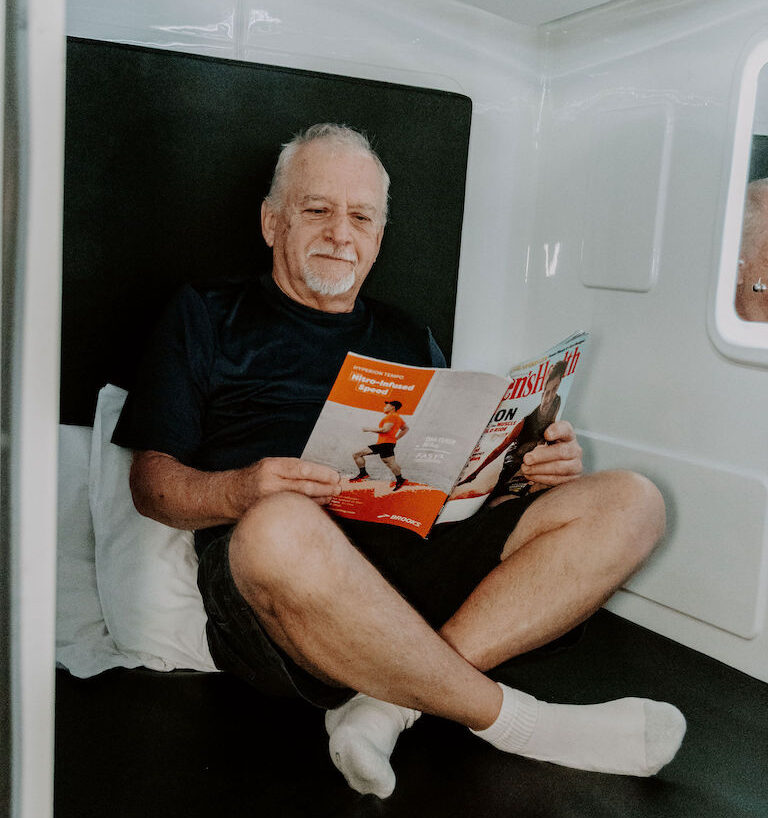 Man sitting inside hyperbaric oxygen chamber reading a magazine.