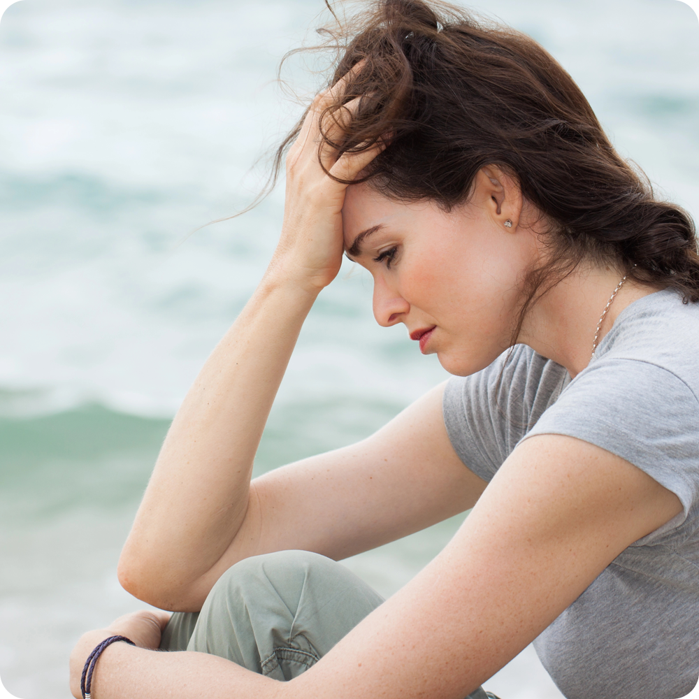 Woman looking tired and frustrated, resting her head on her hand.